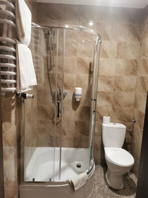 Un baño con ducha de vidrio, bañera y retrete.