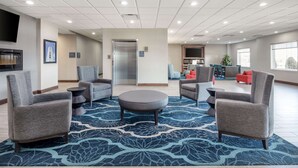 A spacious lobby with grey armchairs, a round ottoman, and a blue patterned rug. - Best Western Plus Owensboro (Owensboro)