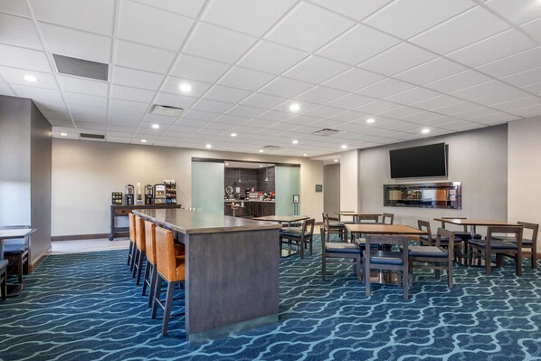 A hotel lobby with a bar area, seating arrangements, and a kitchen visible through a glass partition. - Best Western Plus Owensboro (Owensboro)