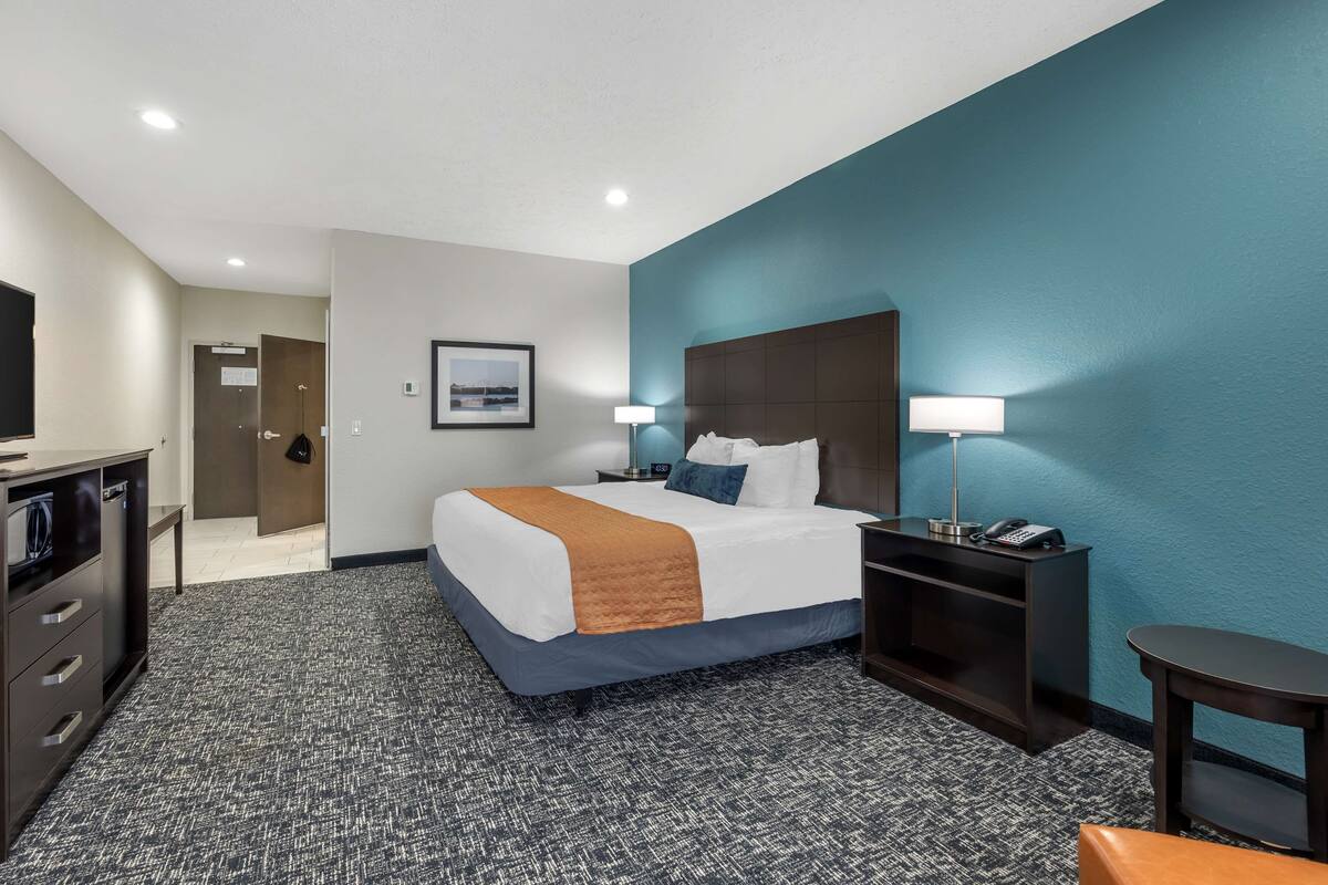 Una habitación de hotel con una cama, mesitas de noche, un escritorio y una silla.