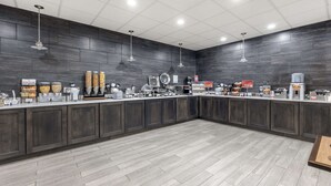 A modern kitchen area with a long counter, various appliances, and storage cabinets. - Best Western Plus Owensboro (Owensboro)