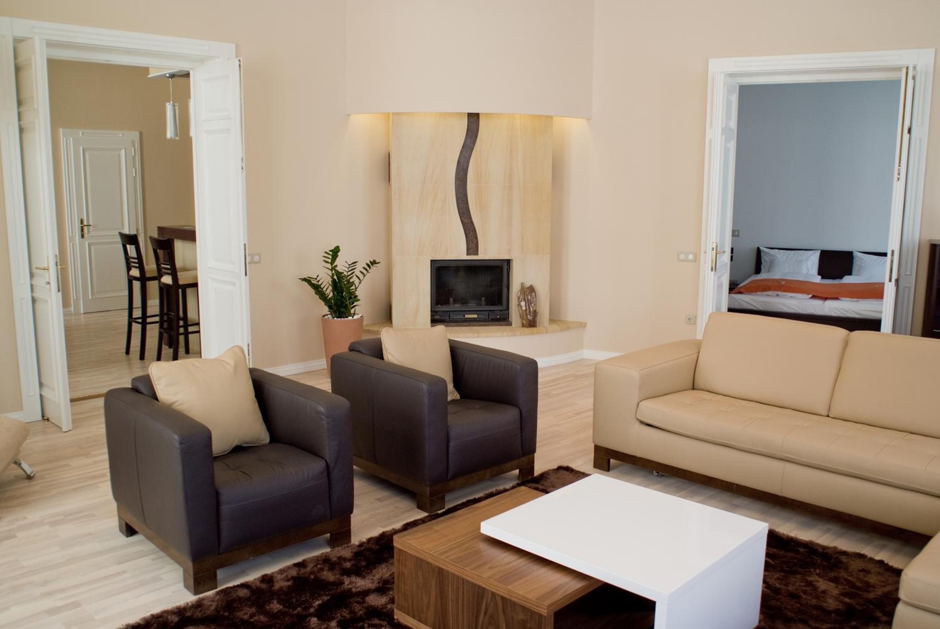 A modern living room with a sofa, two armchairs, a coffee table, a TV, and a fireplace.