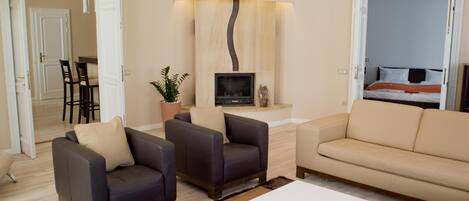 A modern living room with a sofa, two armchairs, a coffee table, a TV, and a fireplace.
