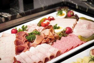 Una tabla de embutidos con diversos tipos de carne, queso y adornos.