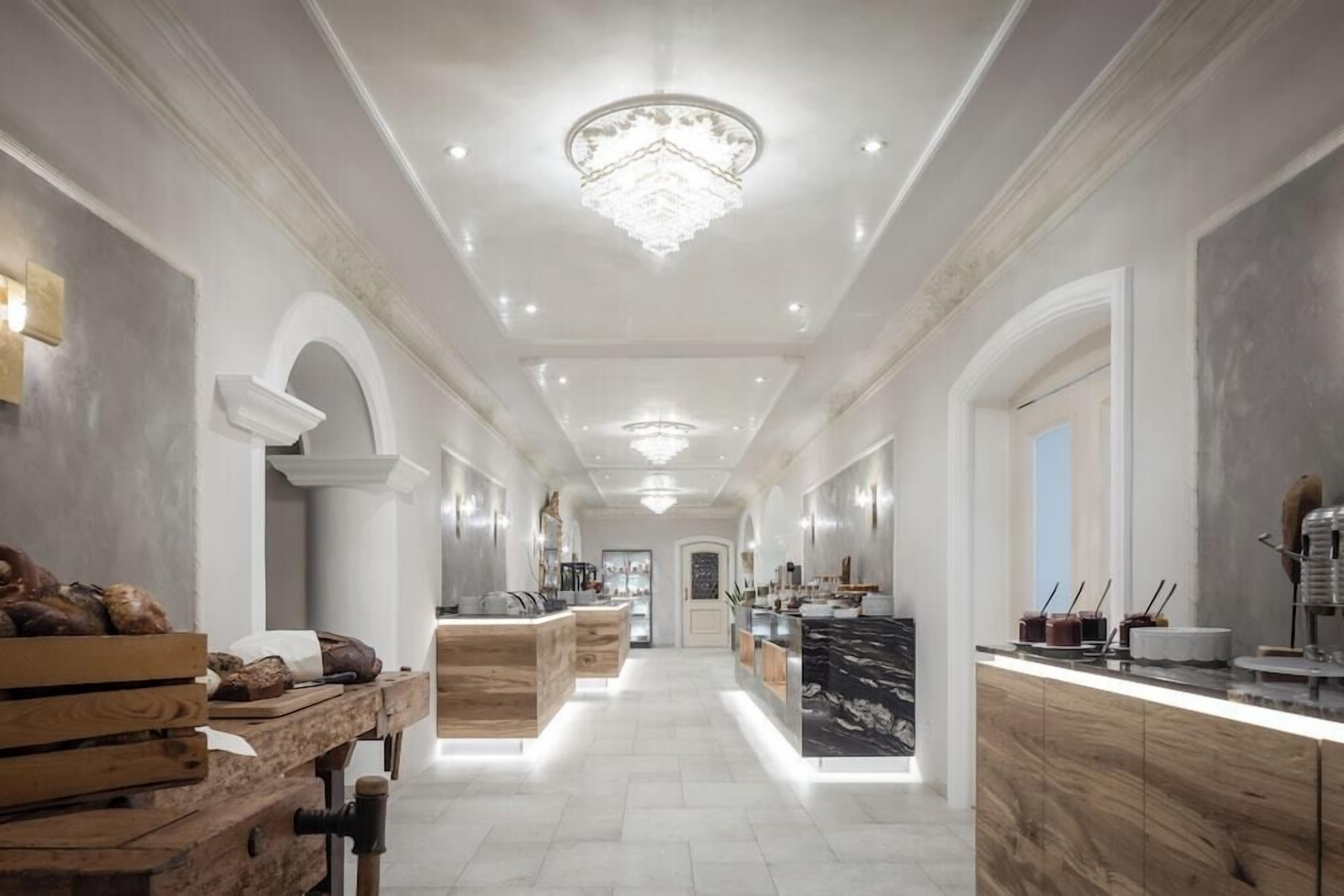 A modern kitchen with a central island, wooden cabinetry, and a chandelier.