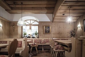 Un intérieur en bois avec un espace salon doté de bancs, des luminaires suspendus et une fenêtre agrémentée de plantes.