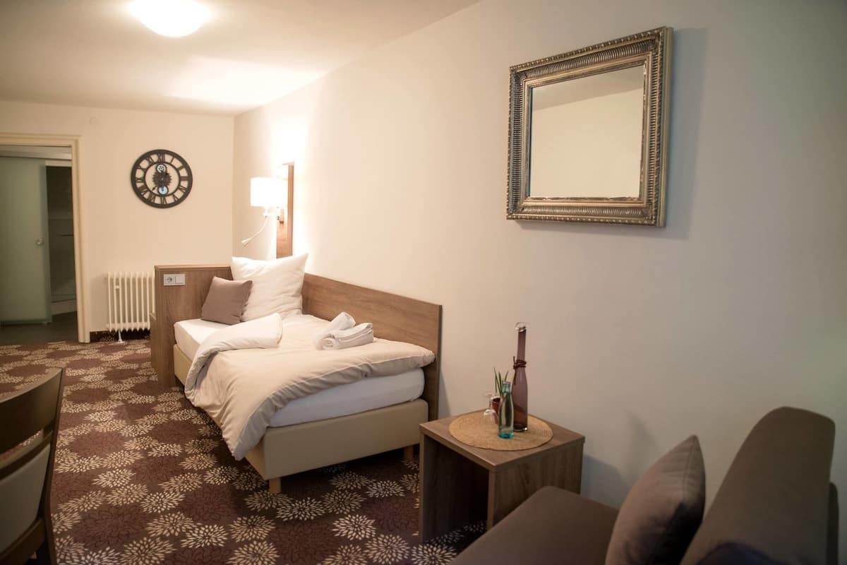 Hotellihuone, jossa on sänky, yöpöytä ja peili seinällä.