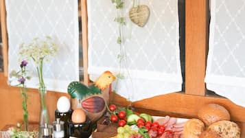 Ein Holztisch mit einer Wurstplatte, einer Blumenvase und einer hängenden Pflanze.