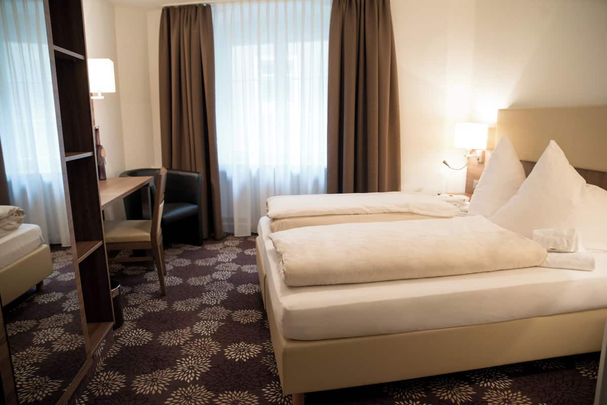 Hotellihuone, jossa on sänky, työpöytä, tuoli ja pieni pöytä.