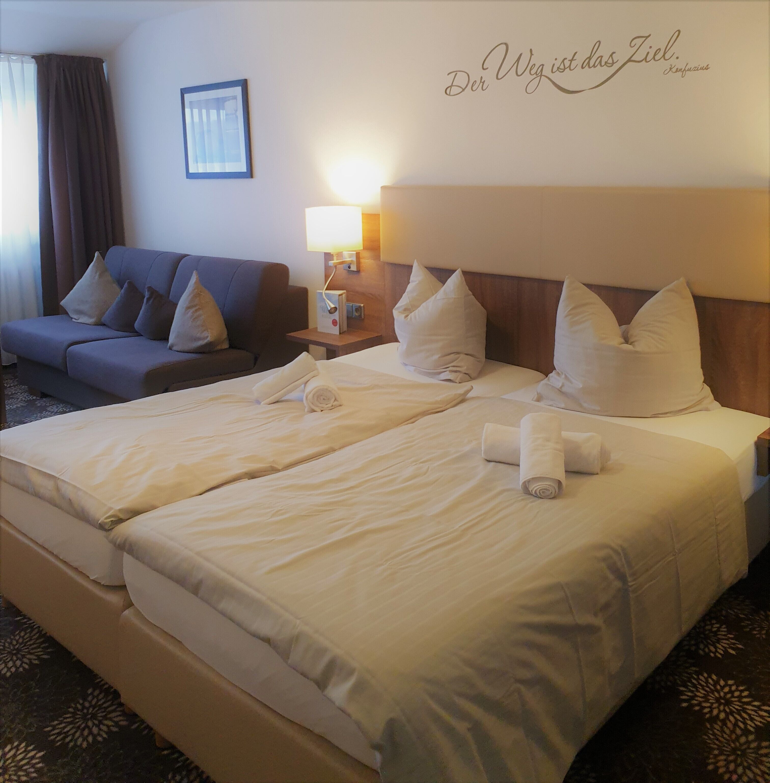 Una habitación de hotel con una cama grande, un sofá y una lámpara fijada a la pared.
