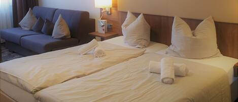 Una habitación de hotel con una cama grande, un sofá y una lámpara fijada a la pared.
