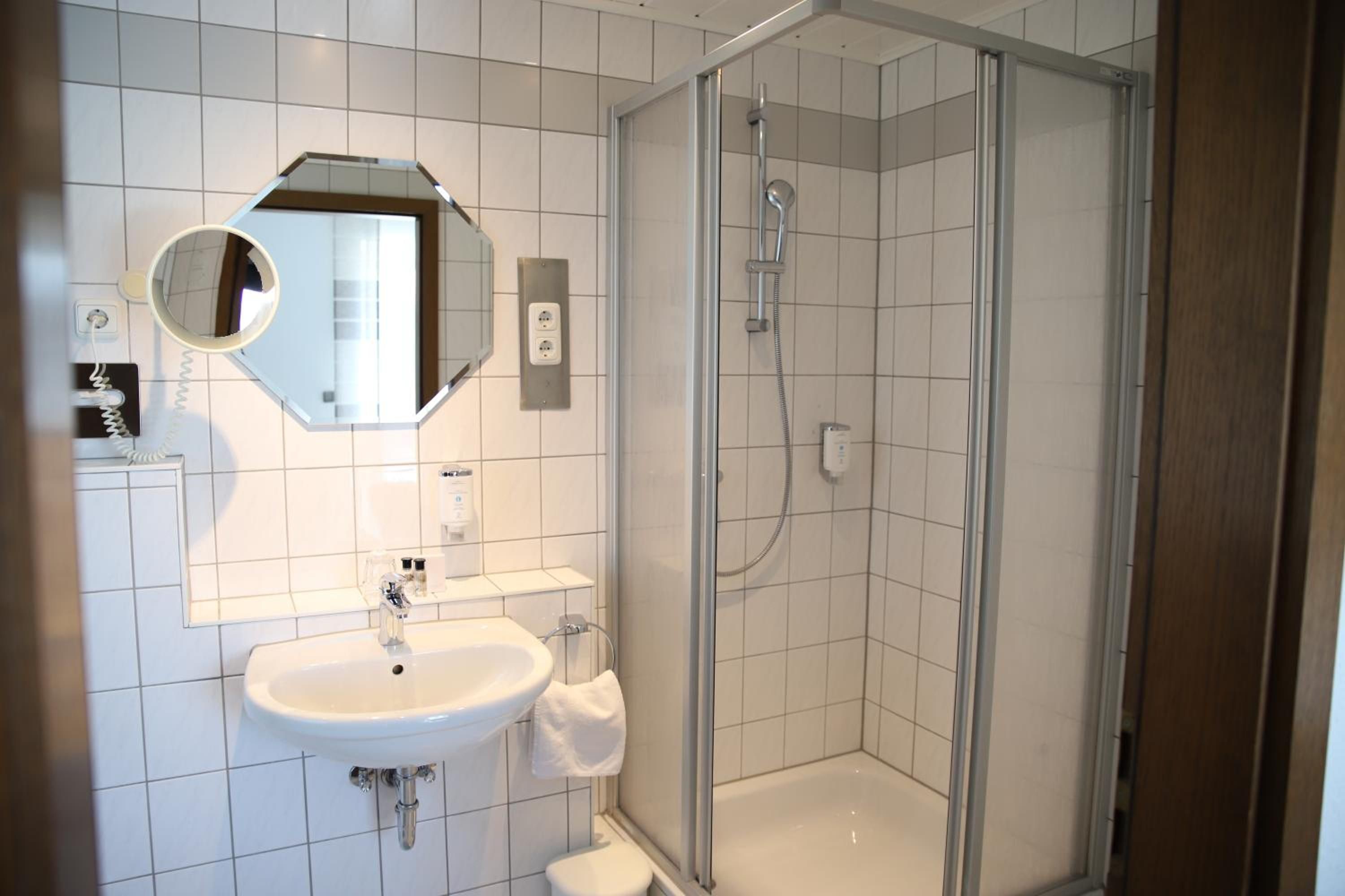 A modern bathroom with a glass-enclosed shower, a white sink, and a mirror above the sink.