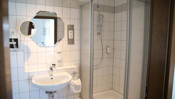 A modern bathroom with a glass-enclosed shower, a white sink, and a mirror above the sink.