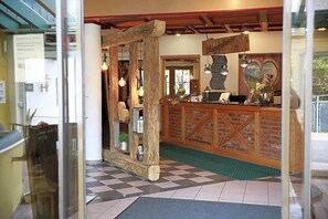 A reception area with a checkered floor, wooden reception desk, and a heart-shaped decoration on the wall.