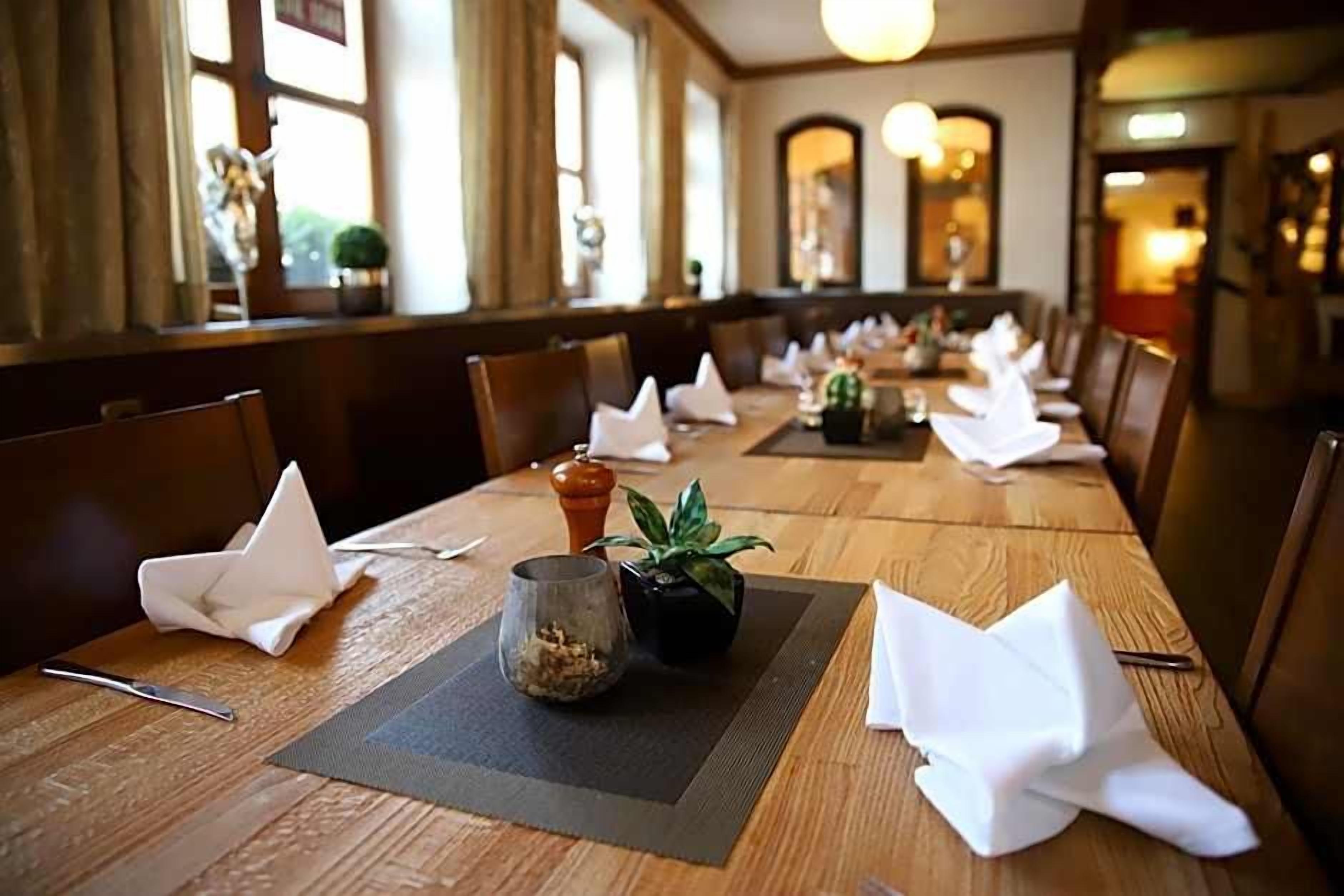 A dining table set with white napkins, a small potted plant, and a glass container.