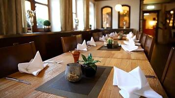 A dining table set with white napkins, a small potted plant, and a glass container.