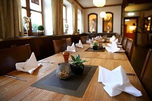 Una mesa de comedor con servilletas blancas, una pequeña planta en maceta y un recipiente de vidrio.