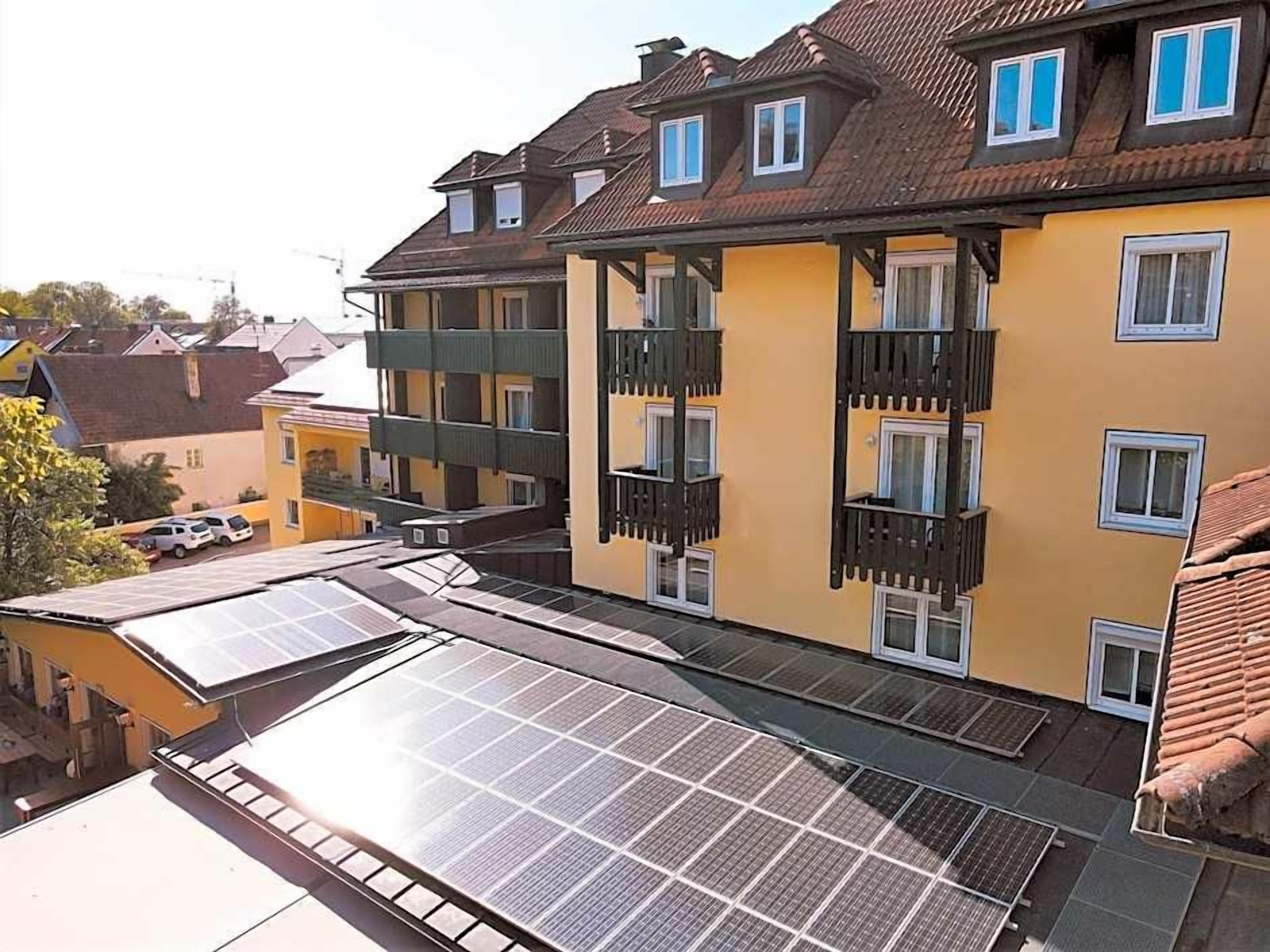 A multi-story building with balconies and solar panels on the roof.