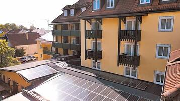 A multi-story building with balconies and solar panels on the roof.