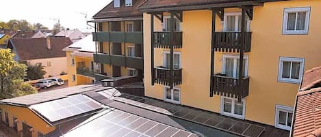 A multi-story building with balconies and solar panels on the roof.