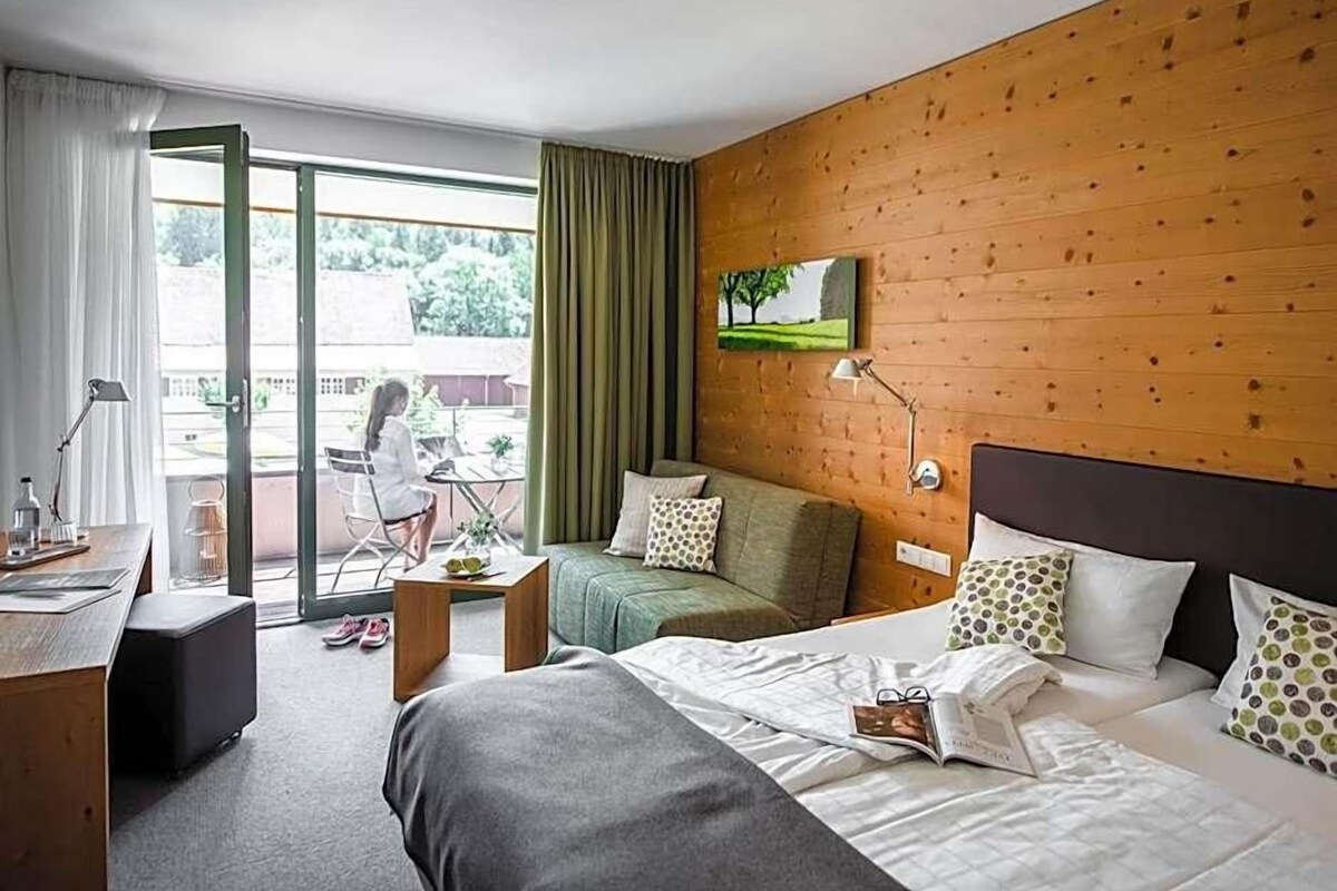 Une chambre d’hôtel équipée d’un lit, d’un bureau, d’une chaise, d’une petite table et offrant une vue sur l’extérieur.
