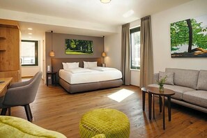 A hotel room with a bed, a sofa, a small table, and a chair.