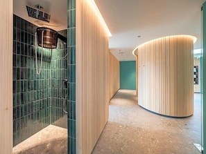 A modern bathroom with a shower, a curved wooden wall, and a tiled floor. - Hofgut Farny (Kisslegg)