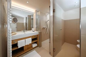 Une salle de bain moderne avec une douche à parois de verre, un meuble-lavabo avec un miroir et un porte-serviettes, et des toilettes.