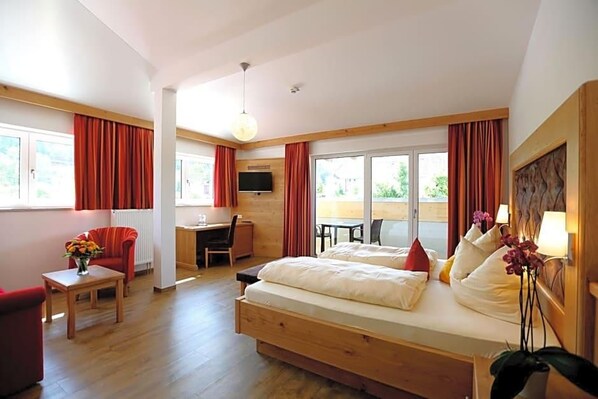 A hotel room with a bed, a desk, a chair, and a TV.