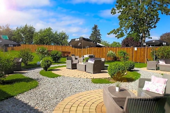An outdoor patio area with wicker furniture, a wooden fence, and a gravel pathway.