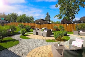An outdoor patio area with wicker furniture, a wooden fence, and a gravel pathway.