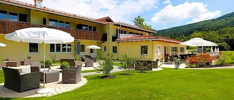 Um hotel com área externa, jardim e vista para as montanhas.