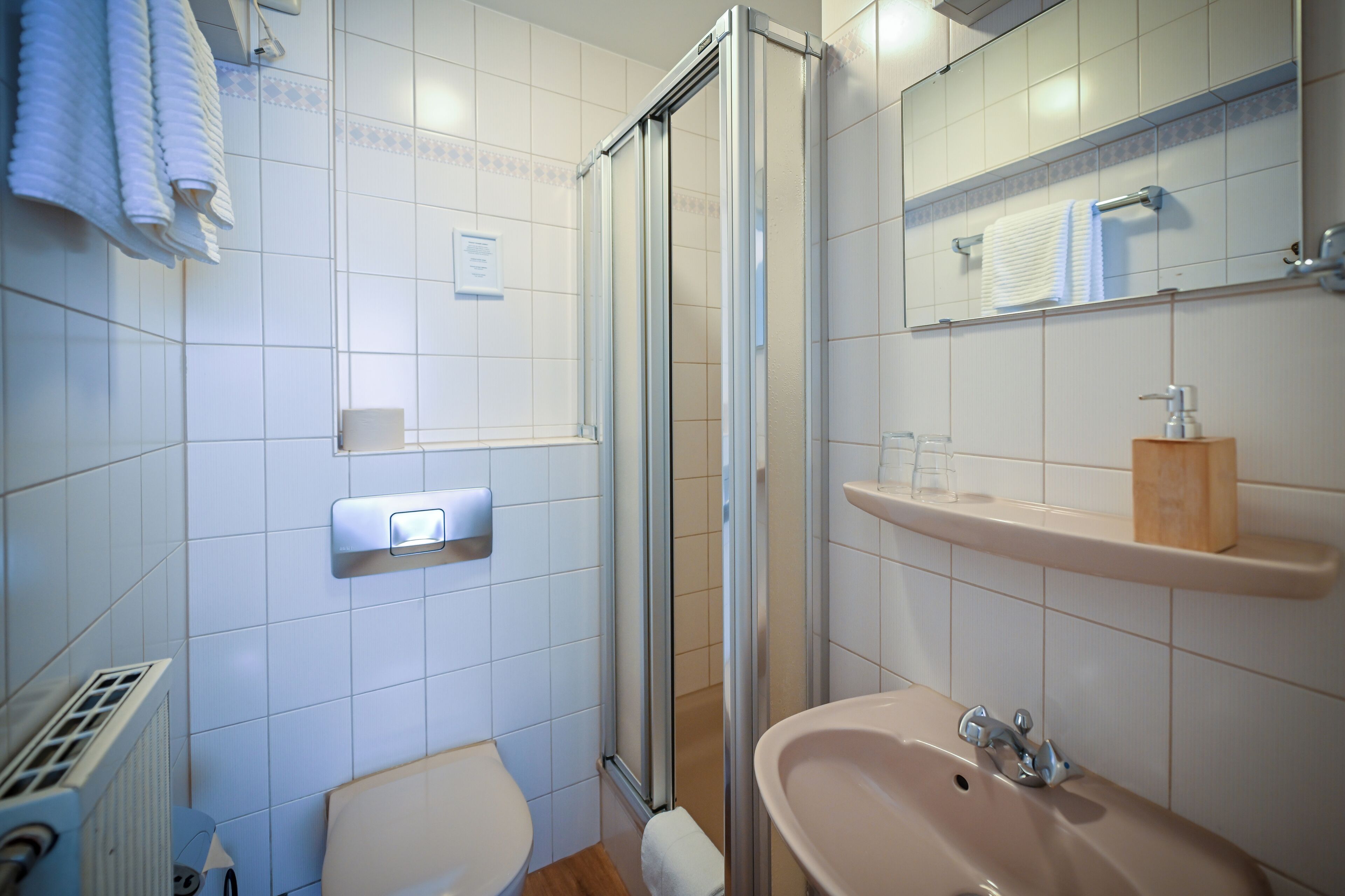 Un baño con inodoro, lavabo, espejo, toallero y cabina de ducha.