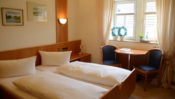 A hotel room with a double bed, two chairs, a small table, and a window with curtains.