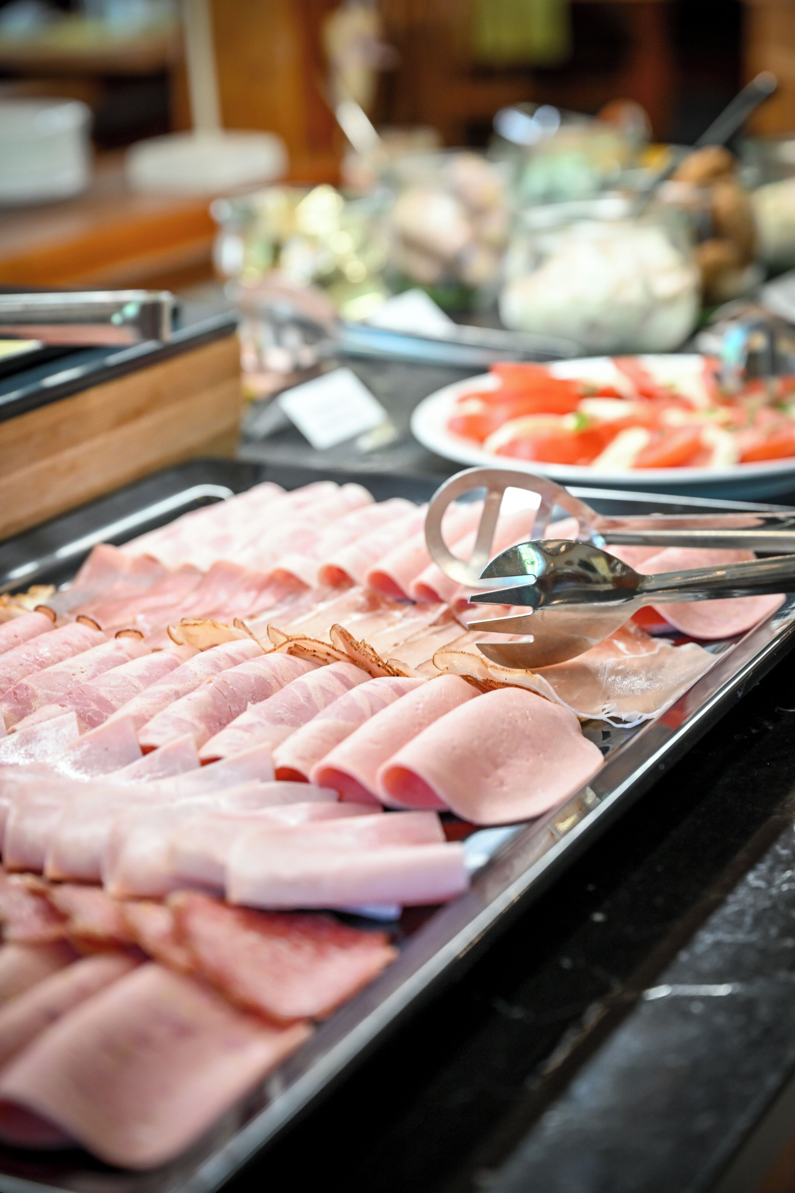 Ein Buffet mit verschiedenen Fleischsorten und einem Glasbehälter im Hintergrund.