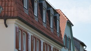 A hotel named "Hotel Mainblick Garnis" with a traditional European architectural style, featuring a tiled roof, shuttered windows, and a cobblestone street in front.
