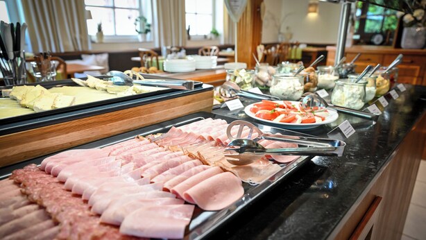 A buffet with various meats and cheeses.