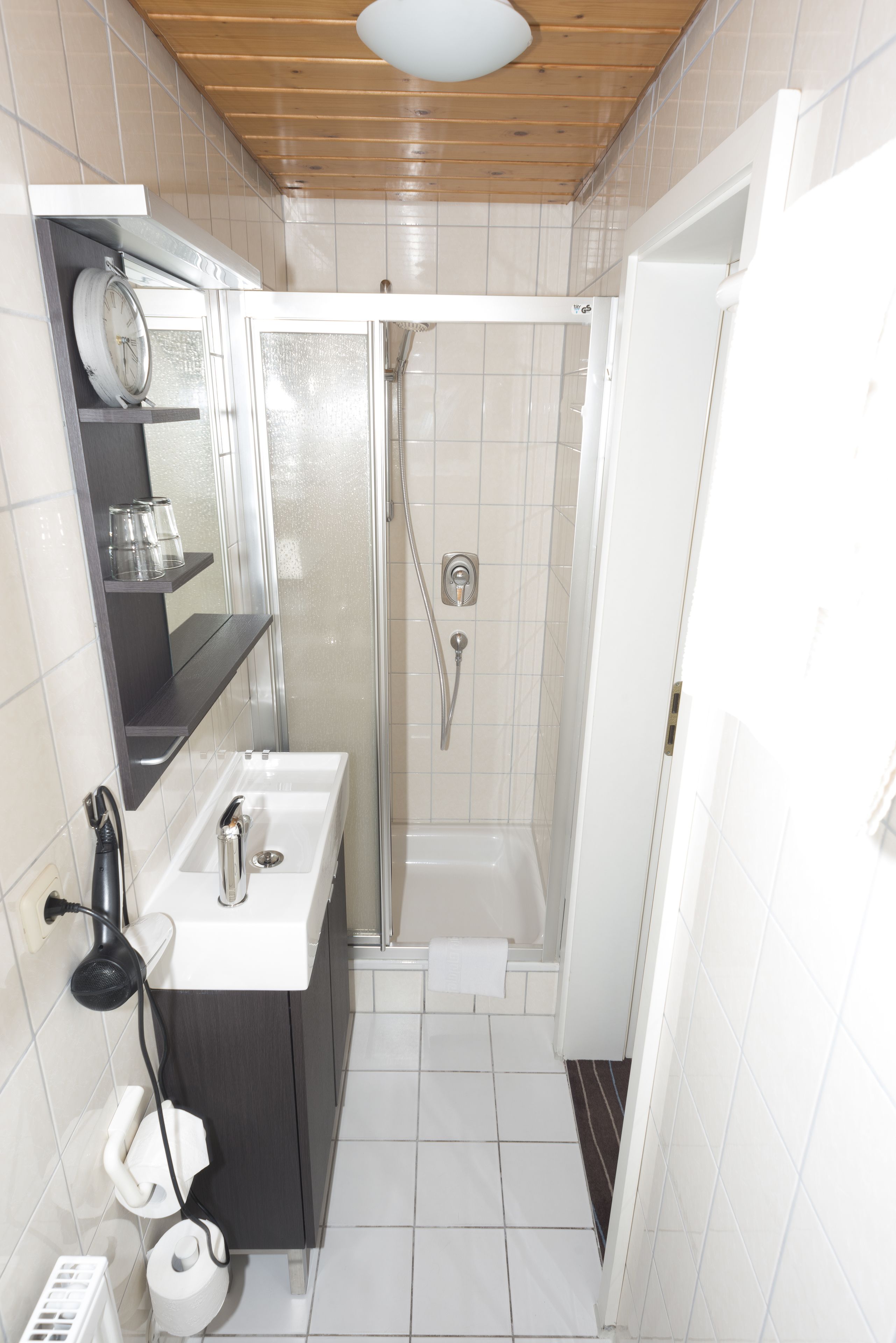 Un baño pequeño con ducha, lavamanos y espejo.