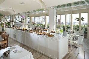 A modern kitchen with a buffet setup, large windows, and a view of the sea. - Gemma (Riccione)