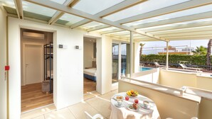 Uma varanda com piscina, uma mesa com café da manhã e um quarto com beliche.