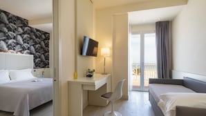 Quarto de hotel com duas camas, uma escrivaninha com cadeira, televisão e varanda com cortinas.