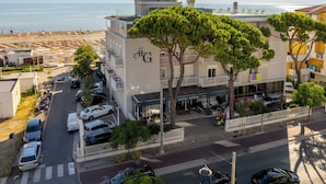 Hotel com vista para a praia, vários espaços de estacionamento e uma passarela para pedestres.