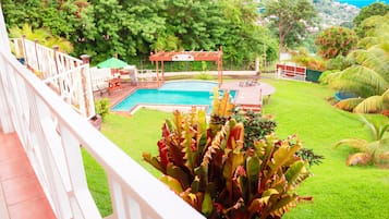 Relax by the pool surrounded by lush greenery and a beautifully manicured lawn.