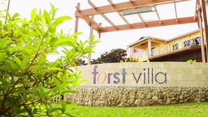 A stone wall with the text "forsvilla" and a wooden pergola structure. - Forst Villa (Kingstown)