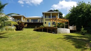 A two-story building with a covered patio area and a stone wall with the name 'Torstvilla'. - Forst Villa (Kingstown)