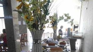 A buffet table with various food items and a decorative vase. - Alzira Granada Hotel (Sao Lourenco)