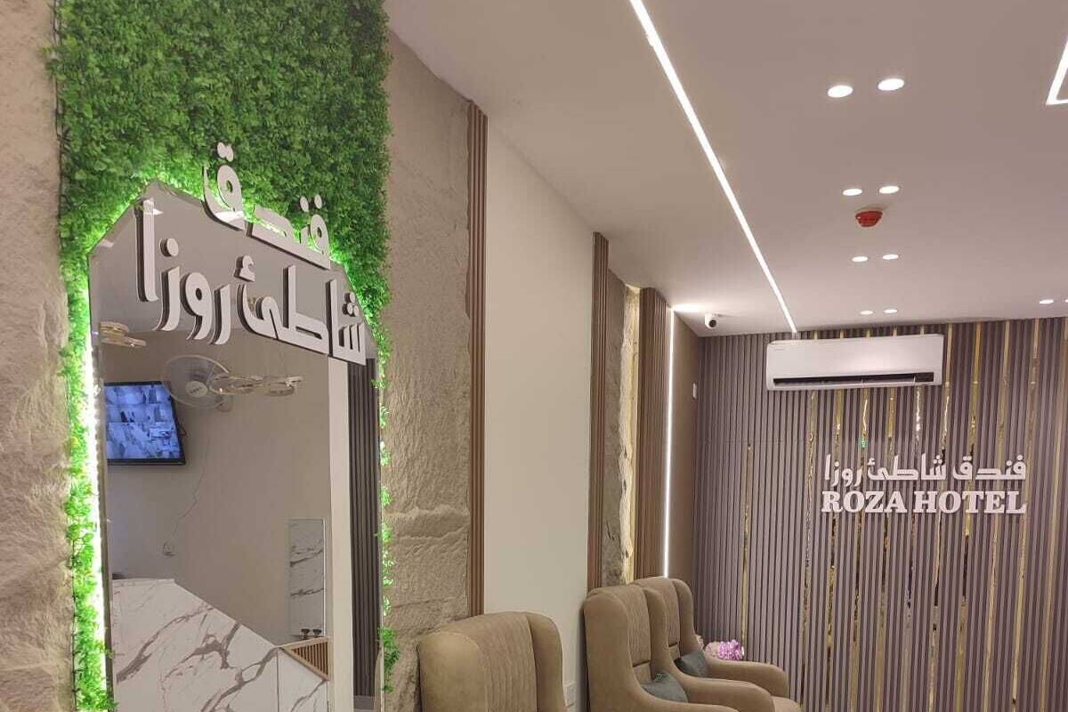 A hotel reception area with a reception desk, a TV, and a seating area with sofas and a small table.