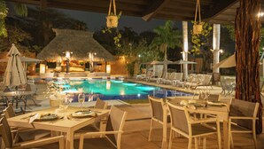 An outdoor dining area with tables and chairs, a pool, and lounge chairs.