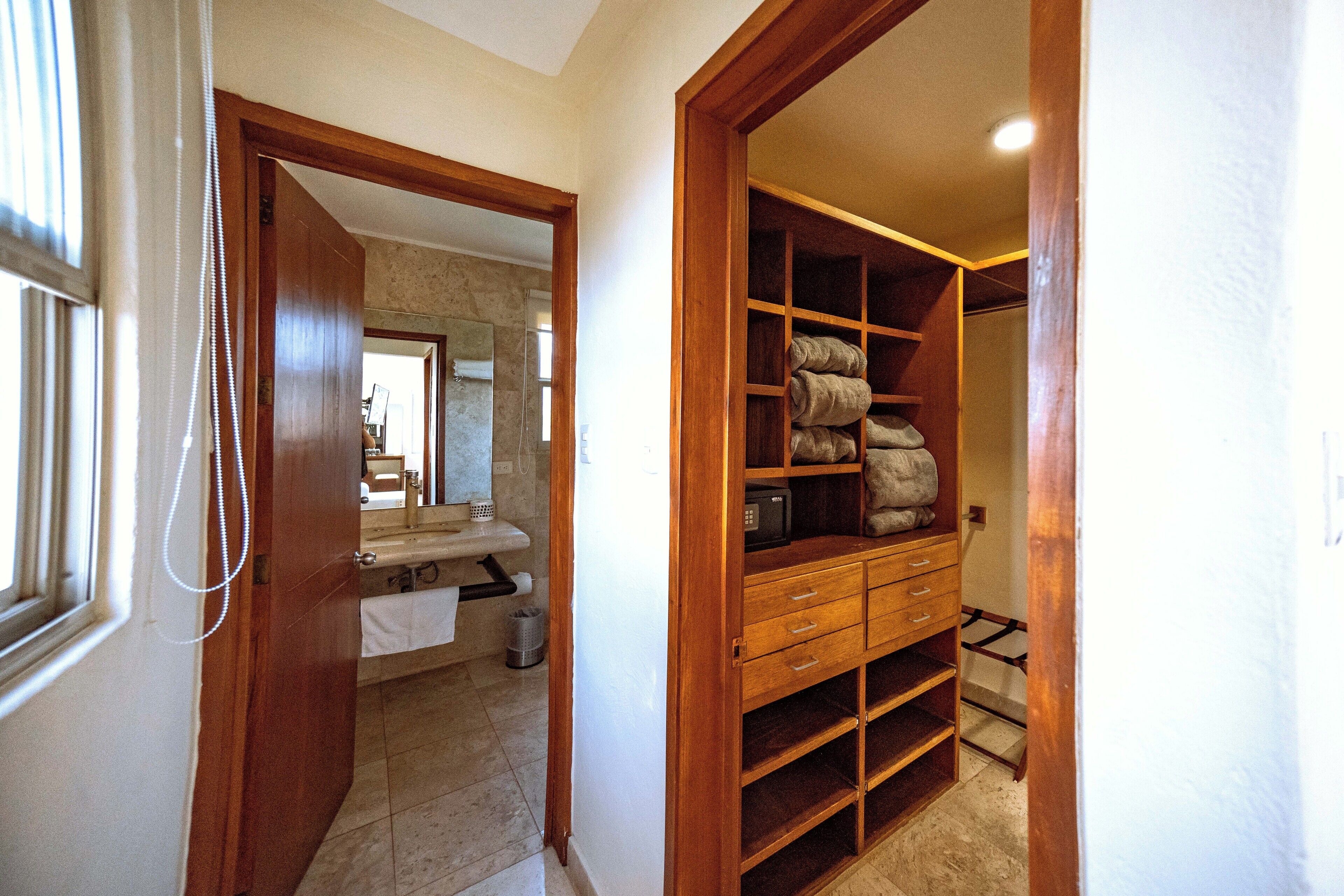 A hallway with a wooden door leading to a bathroom and a closet with shelves and drawers.
