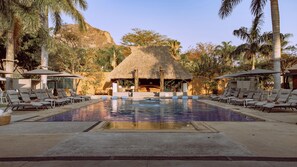 A pool area with lounge chairs, a thatched-roof structure, and palm trees. - Alilo by Muuk (Tepoztlán)
